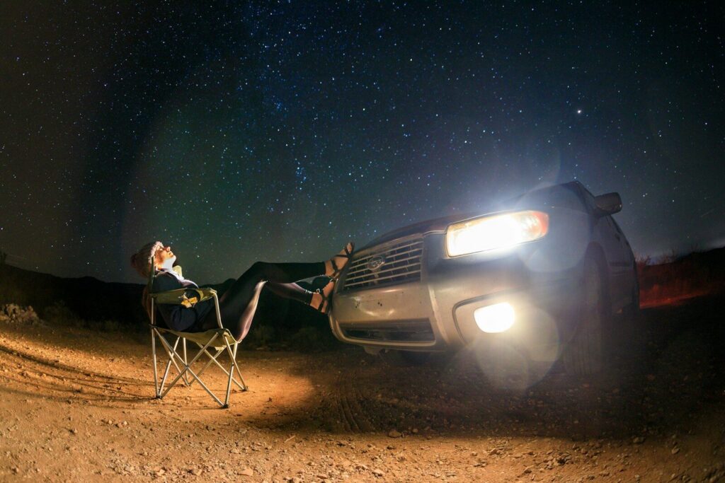 man and woman sitting on camping chairs beside black suv during night time