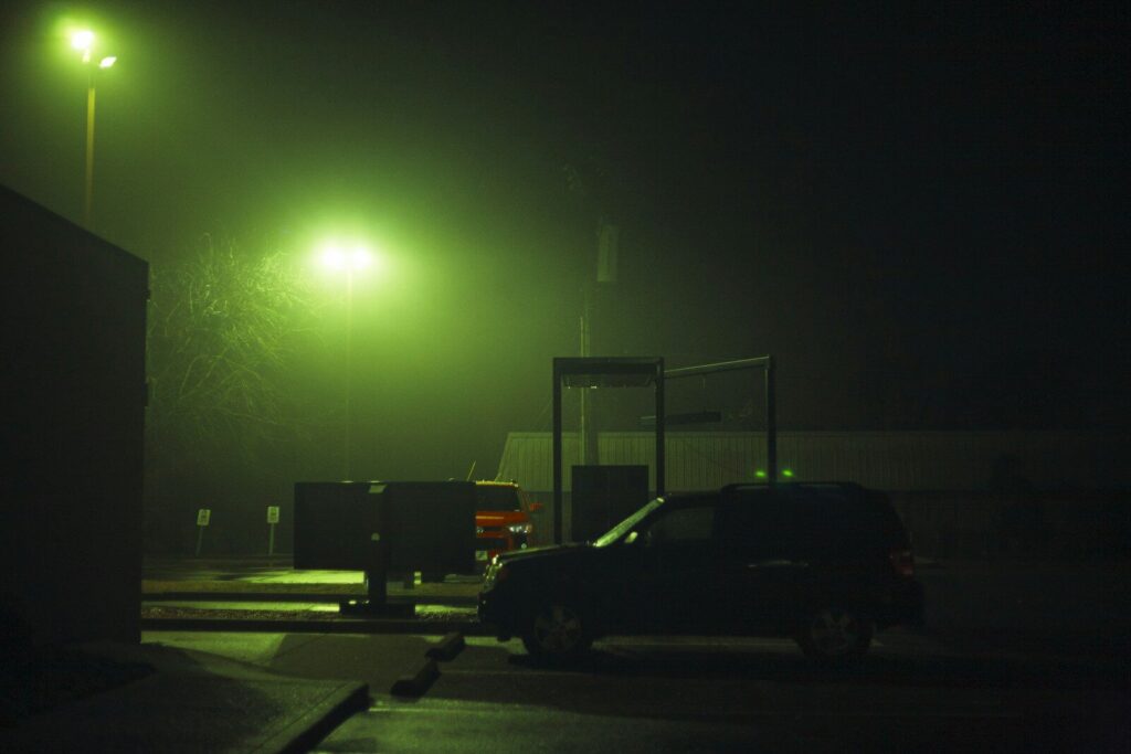A car parked under streetlights at night while stealth camping.